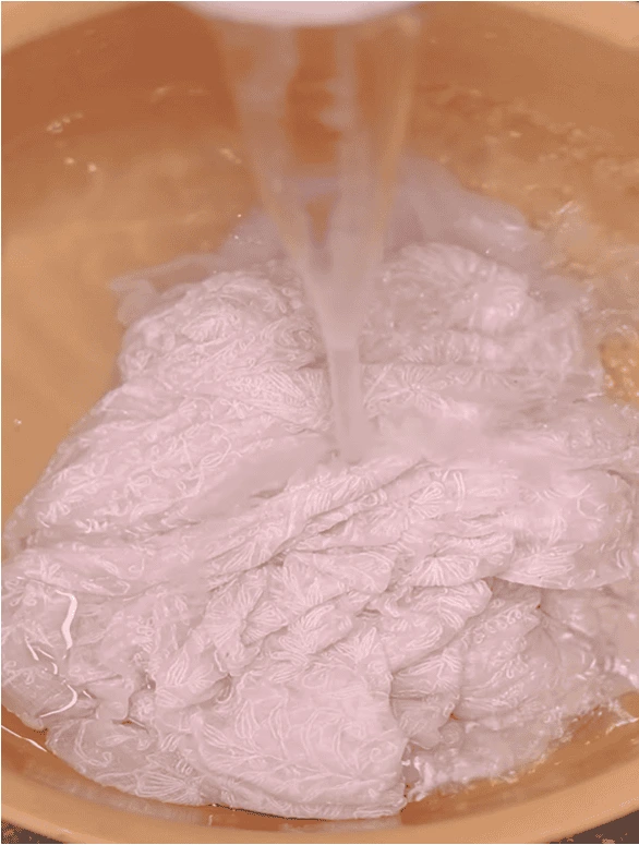 Water pouring over chikankari worked fabric