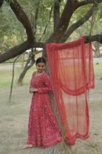 Woman in red anarkali by tree.
