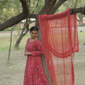 Woman in red anarkali by tree.