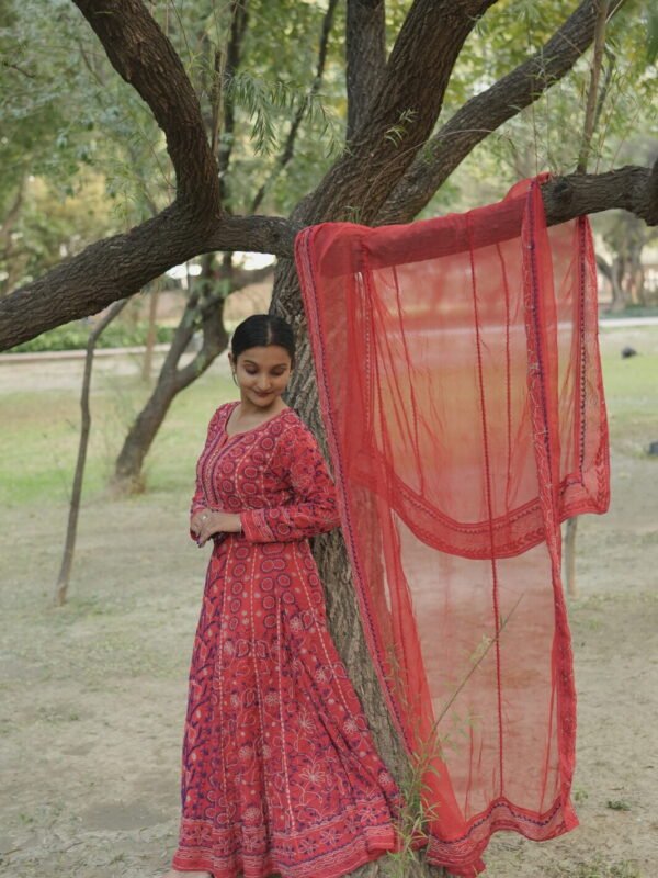 Woman in red anarkali by tree.